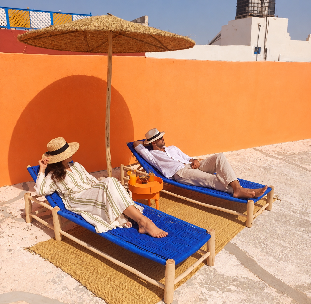 Espace détente sur une terrasse marocaine avec transats et parasol en paille
